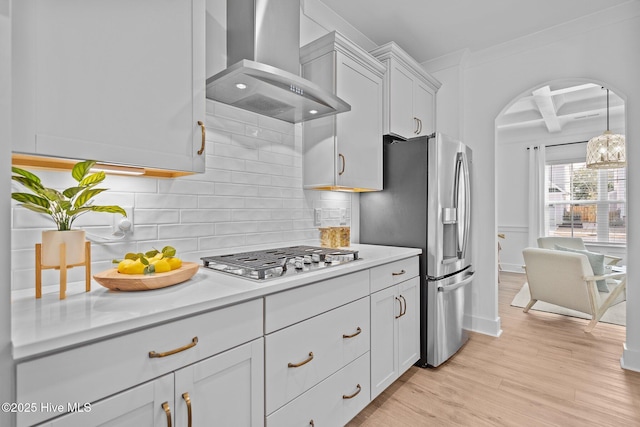 kitchen with wall chimney exhaust hood, light hardwood / wood-style flooring, stainless steel appliances, beam ceiling, and backsplash