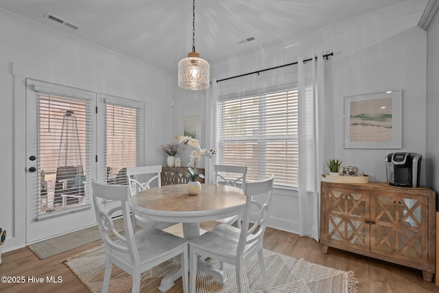 dining room with ornamental molding and light hardwood / wood-style floors