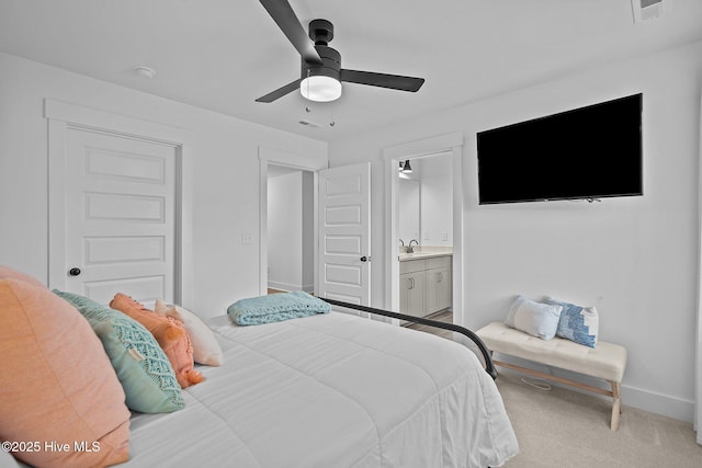 bedroom featuring light carpet, sink, ensuite bath, and ceiling fan