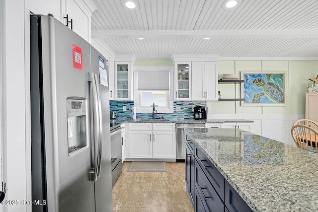 kitchen featuring tasteful backsplash, glass insert cabinets, beamed ceiling, appliances with stainless steel finishes, and white cabinets