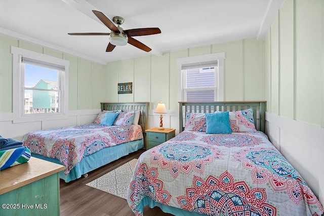 bedroom with wood finished floors, a ceiling fan, and a decorative wall