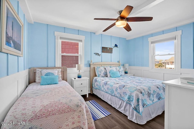 bedroom featuring dark wood-type flooring, a decorative wall, and a ceiling fan