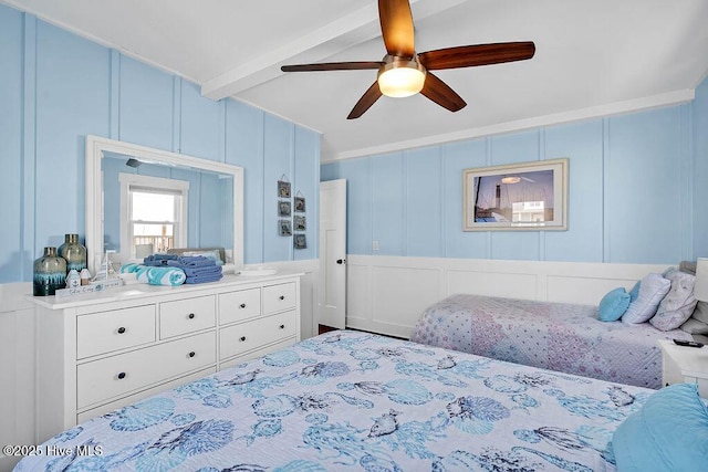 bedroom featuring beam ceiling, ceiling fan, crown molding, and a decorative wall