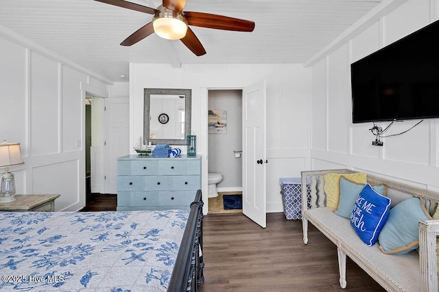 bedroom with a decorative wall, connected bathroom, a ceiling fan, and dark wood-style flooring