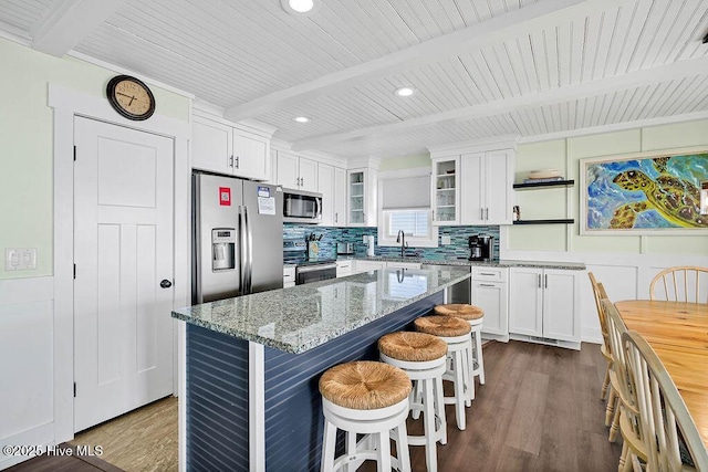 kitchen featuring beamed ceiling, appliances with stainless steel finishes, white cabinetry, and a sink