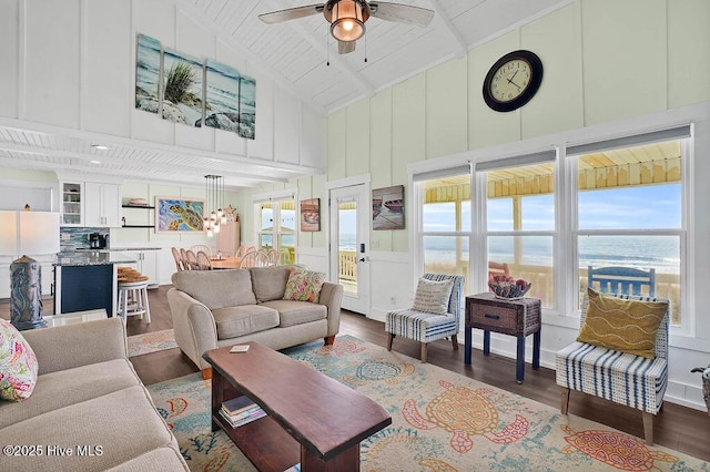 living room featuring dark wood-type flooring, a decorative wall, a ceiling fan, and high vaulted ceiling