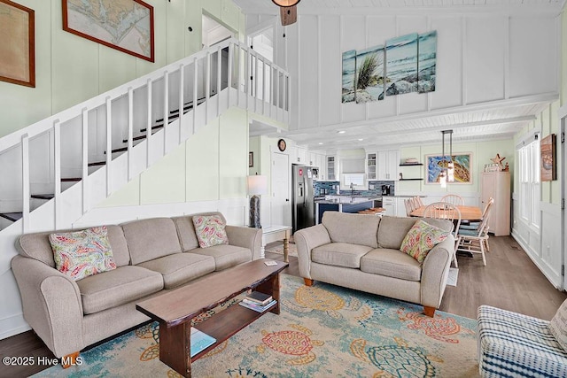 living room with stairway, a high ceiling, wood finished floors, and a decorative wall