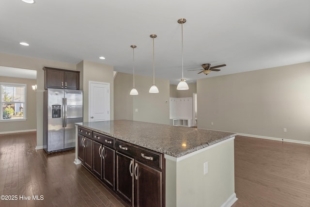 kitchen with a center island, stainless steel refrigerator with ice dispenser, dark wood-type flooring, dark brown cabinets, and baseboards