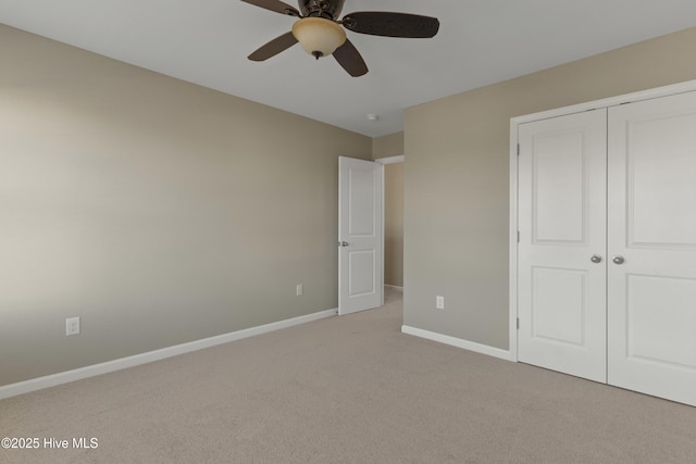 unfurnished bedroom with a closet, light colored carpet, ceiling fan, and baseboards