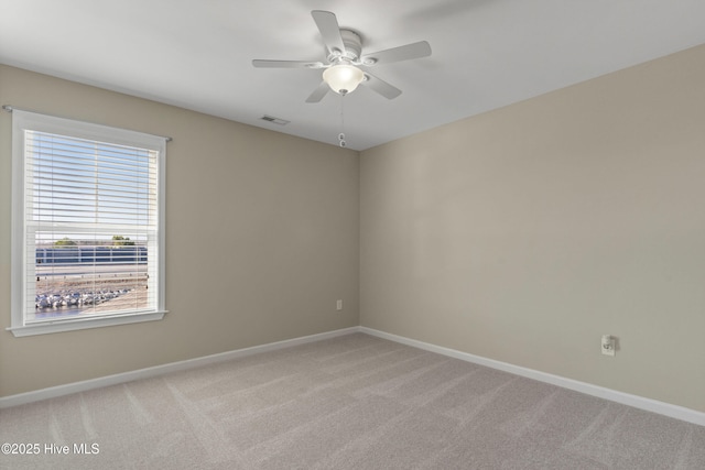 empty room featuring light carpet, a ceiling fan, visible vents, and baseboards