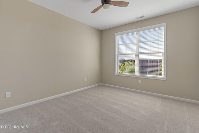 empty room with light colored carpet, ceiling fan, visible vents, and baseboards