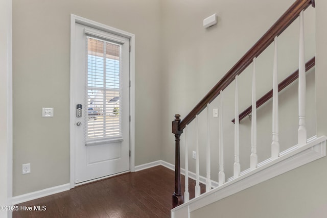 foyer with dark wood-type flooring, stairway, and baseboards