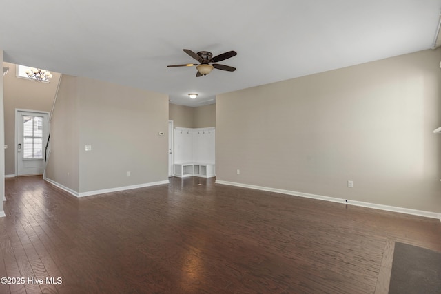 unfurnished living room with dark wood finished floors, baseboards, and ceiling fan with notable chandelier