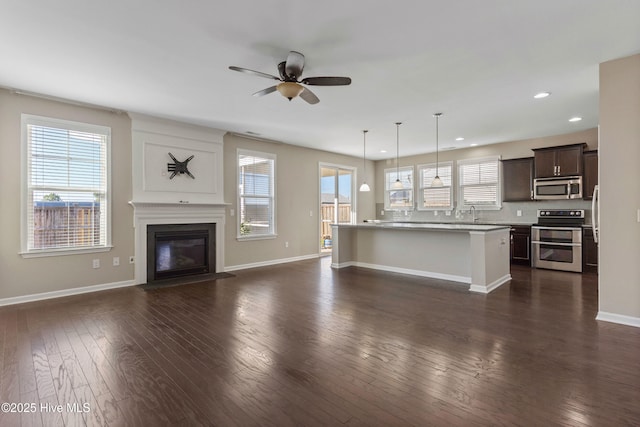 unfurnished living room with plenty of natural light, dark wood finished floors, and a fireplace with flush hearth