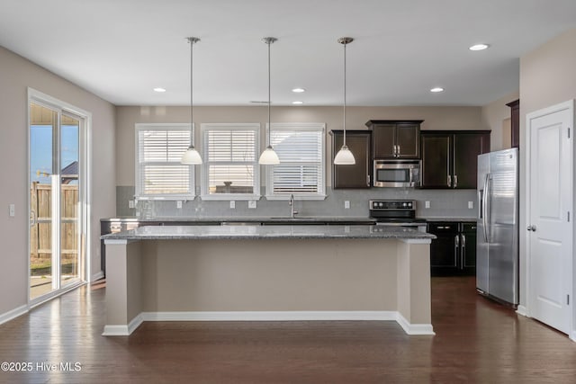 kitchen featuring plenty of natural light, tasteful backsplash, dark wood-style floors, a kitchen island, and appliances with stainless steel finishes