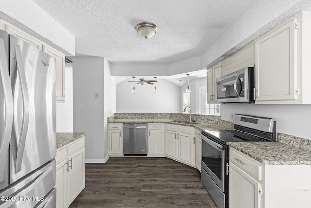 kitchen with hanging light fixtures, stainless steel appliances, sink, a textured ceiling, and dark hardwood / wood-style floors