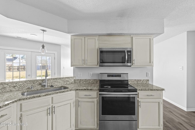 kitchen with stainless steel appliances, dark hardwood / wood-style flooring, light stone counters, and sink