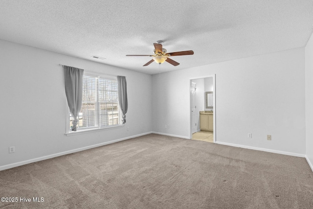 unfurnished bedroom featuring ceiling fan, a textured ceiling, light carpet, and connected bathroom