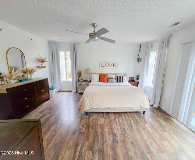 bedroom with hardwood / wood-style flooring, ceiling fan, and a textured ceiling