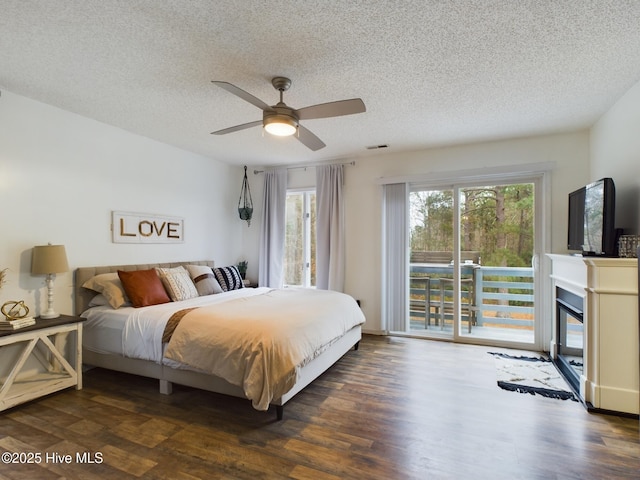 bedroom with ceiling fan, access to outside, a textured ceiling, and dark hardwood / wood-style flooring