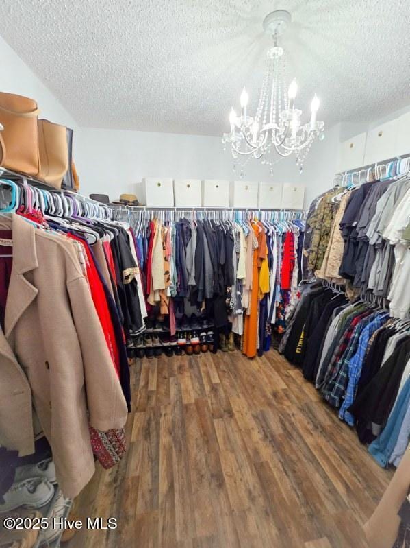 spacious closet with dark hardwood / wood-style floors and a chandelier