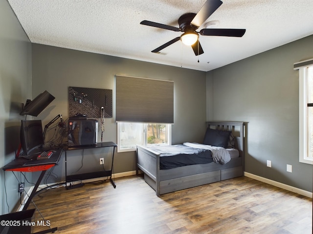 bedroom with hardwood / wood-style flooring, ceiling fan, and a textured ceiling