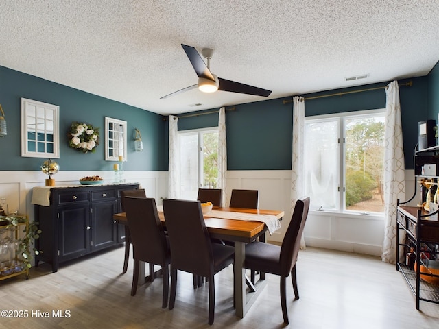 dining area with a textured ceiling, ceiling fan, and light wood-type flooring