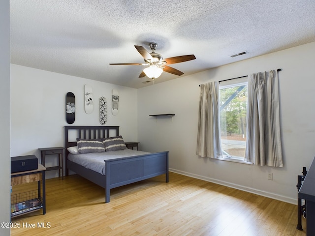 bedroom featuring ceiling fan, light hardwood / wood-style floors, and a textured ceiling