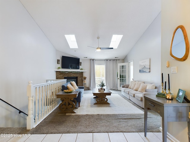 living room with light tile patterned flooring, a skylight, high vaulted ceiling, ceiling fan, and a fireplace