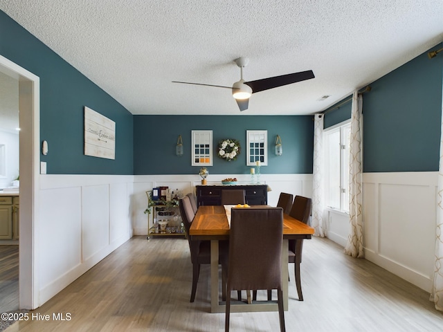 dining area with hardwood / wood-style flooring, a textured ceiling, and ceiling fan