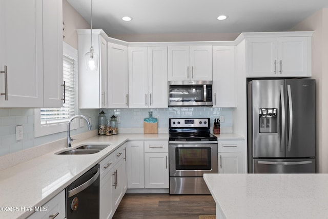 kitchen with white cabinetry, sink, hanging light fixtures, and appliances with stainless steel finishes