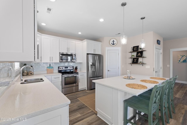 kitchen featuring pendant lighting, sink, white cabinetry, stainless steel appliances, and decorative backsplash