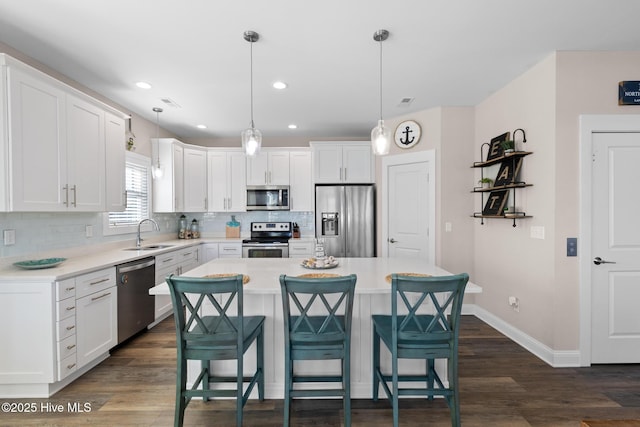 kitchen featuring white cabinetry, hanging light fixtures, a kitchen island, and appliances with stainless steel finishes