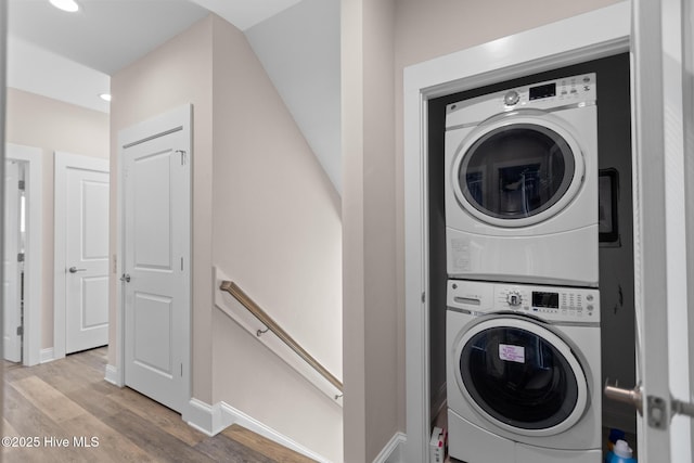 laundry area with stacked washer / dryer and light wood-type flooring