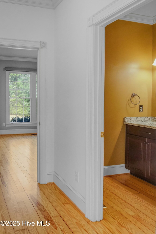 corridor featuring ornamental molding and light hardwood / wood-style flooring