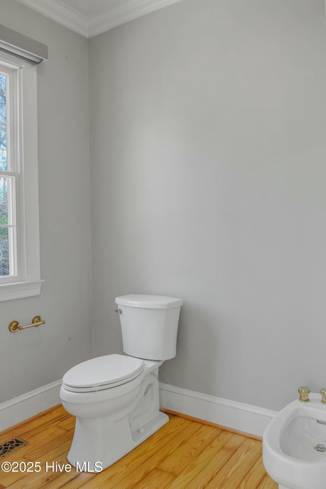 bathroom with hardwood / wood-style flooring, a bidet, crown molding, and toilet