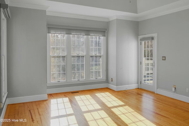 spare room featuring a wealth of natural light, ornamental molding, and light wood-type flooring