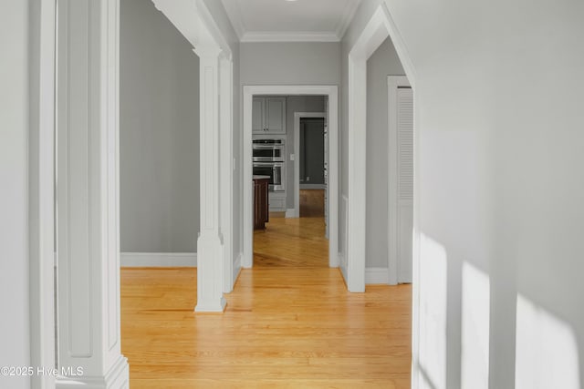 hallway featuring hardwood / wood-style flooring, crown molding, and decorative columns