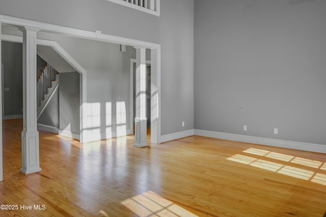 unfurnished living room featuring light hardwood / wood-style floors and decorative columns