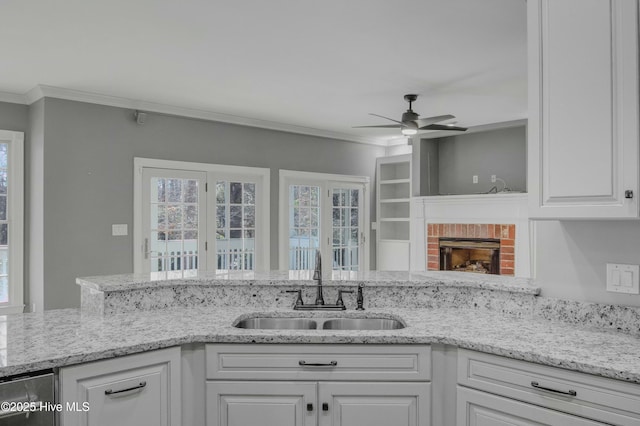 kitchen featuring white cabinetry, a healthy amount of sunlight, ornamental molding, and sink