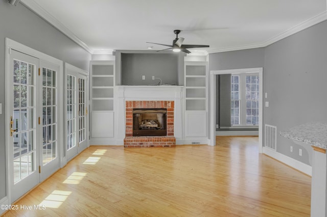 unfurnished living room with crown molding, a fireplace, light wood-type flooring, and a wealth of natural light