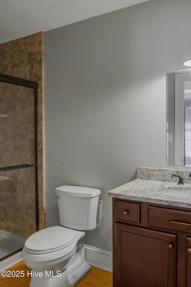 bathroom featuring hardwood / wood-style flooring, vanity, walk in shower, and toilet