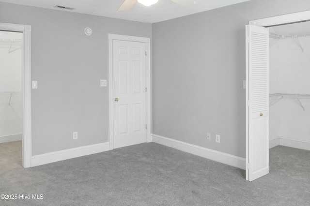 unfurnished bedroom featuring light carpet, a spacious closet, a closet, and ceiling fan