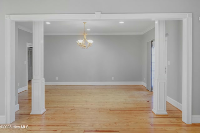 unfurnished dining area with an inviting chandelier, ornamental molding, ornate columns, and light wood-type flooring