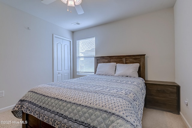 bedroom featuring ceiling fan, light carpet, and a closet