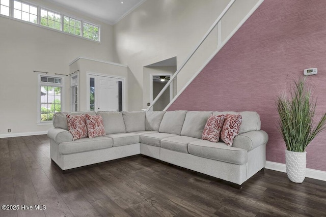 living room featuring baseboards, a towering ceiling, and a wealth of natural light
