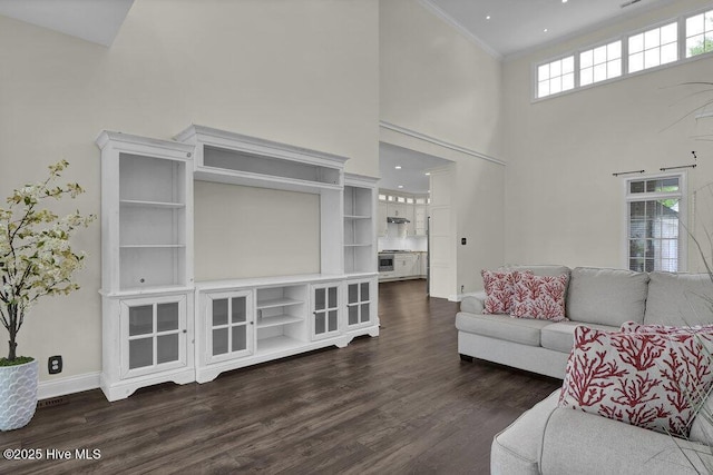 living area featuring ornamental molding, dark wood-style flooring, a towering ceiling, baseboards, and recessed lighting
