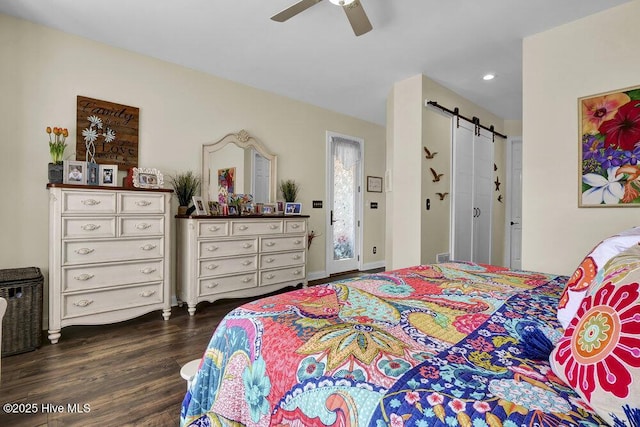 bedroom featuring a barn door, dark wood-type flooring, and ceiling fan