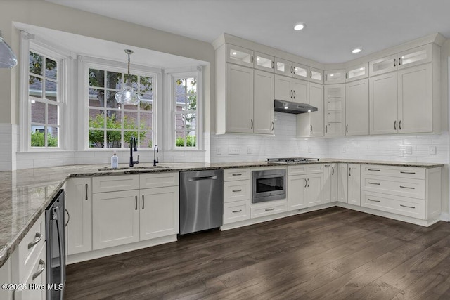 kitchen featuring appliances with stainless steel finishes, a sink, white cabinetry, decorative backsplash, and dark wood-type flooring