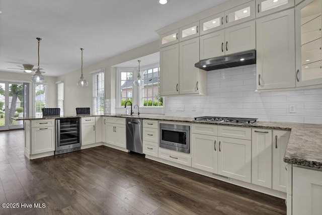 kitchen featuring white cabinets, stainless steel appliances, a peninsula, wine cooler, and under cabinet range hood